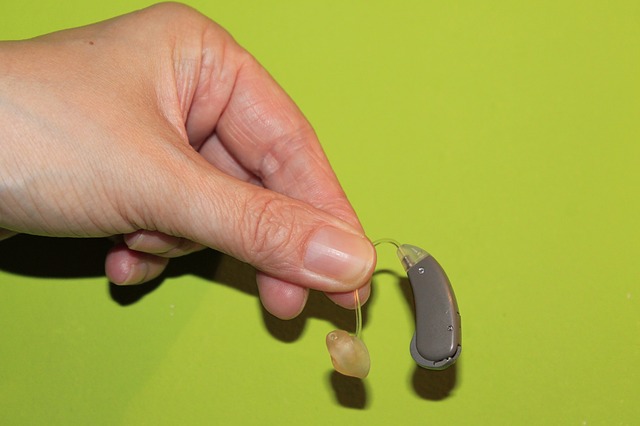 Hand holding a hearing aid against a green background